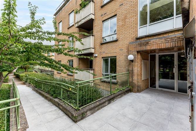Apartment building exterior with brick facade, green railings, and accessible entrance ramp.