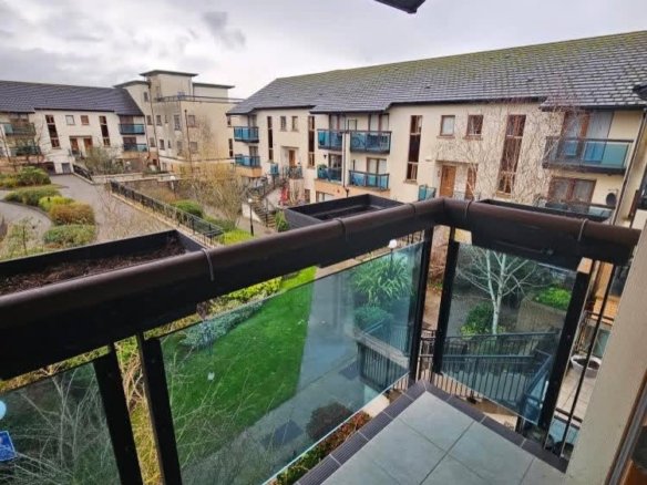 Balcony view of apartment buildings with green spaces in a residential complex on a cloudy day.