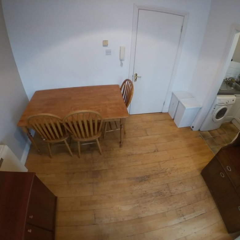 Dining area with wooden table, chairs, and kitchen access in a bright apartment.