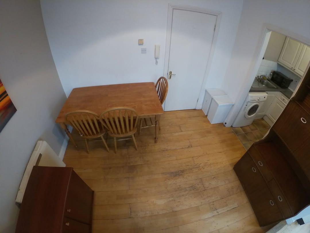 Dining area with wooden table, chairs, and kitchen access in a bright apartment.
