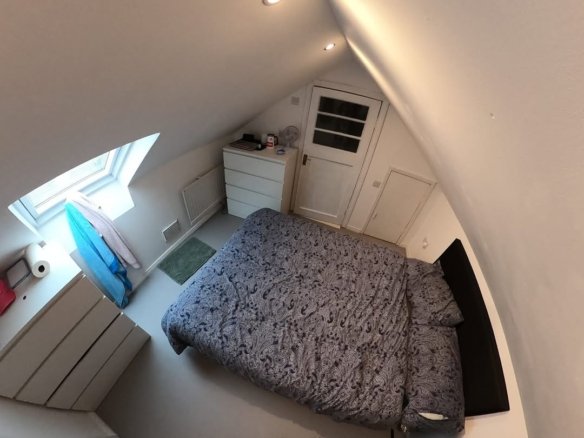 Cozy attic bedroom with bed, dresser, and window. Sloped ceiling.