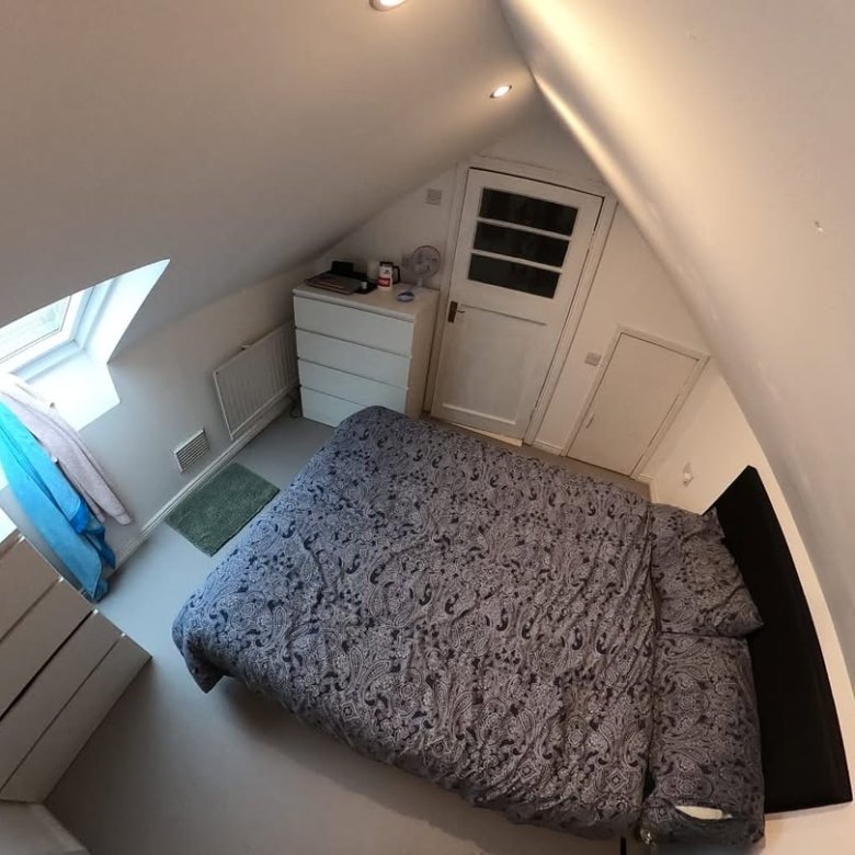 Cozy attic bedroom with bed, dresser, and window. Sloped ceiling.