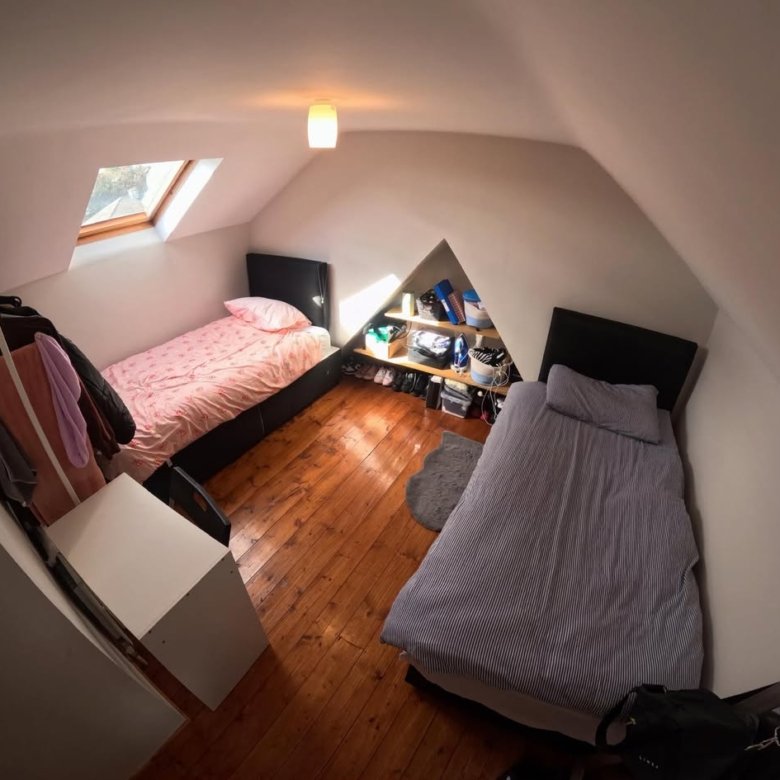 Attic bedroom with two single beds and built-in storage in eaves.