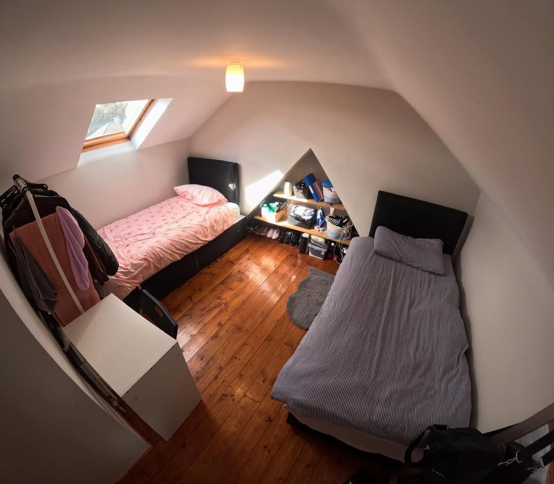 Attic bedroom with two single beds and built-in storage in eaves.