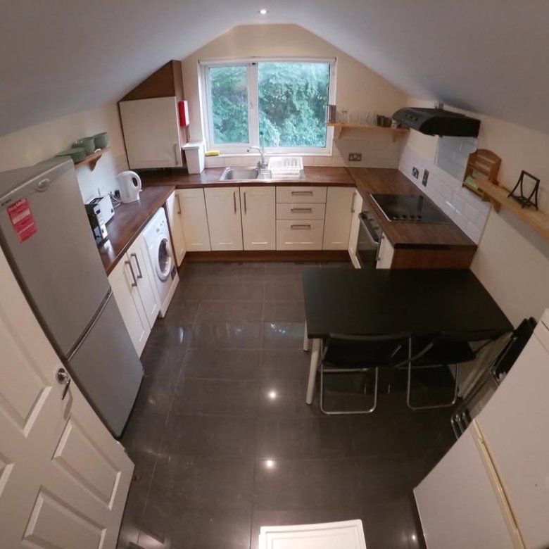 Attic kitchen with white cabinets, dark countertops, and dining table.