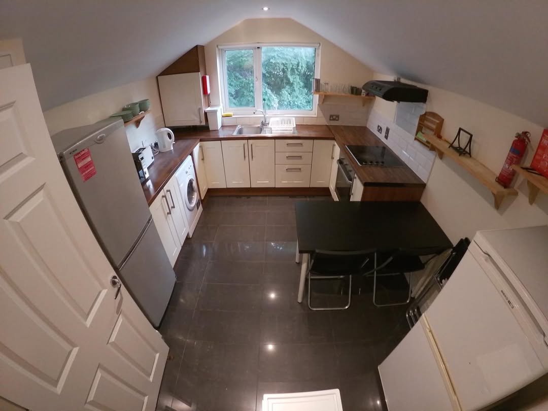 Attic kitchen with white cabinets, dark countertops, and dining table.