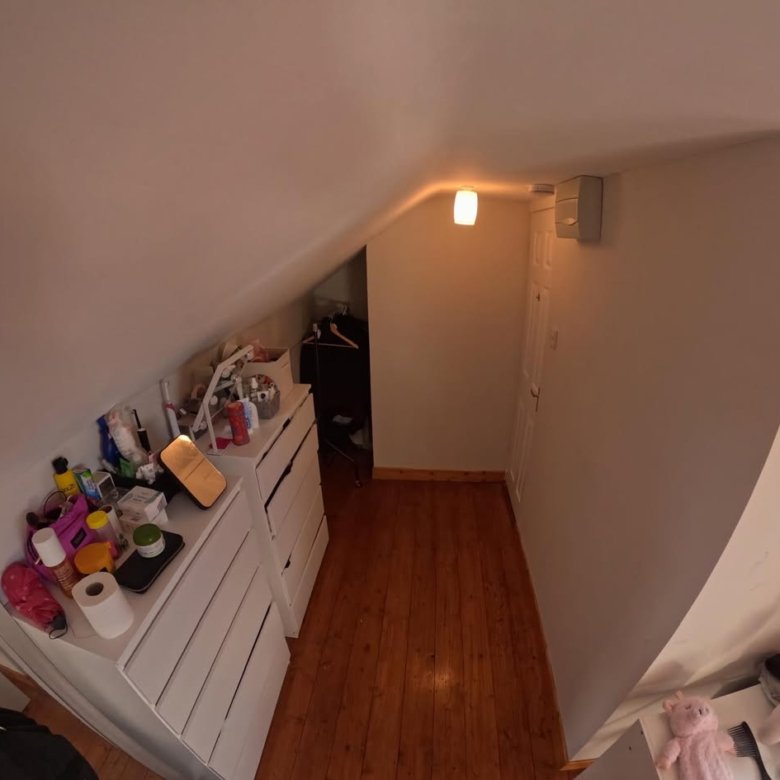 Attic storage space with white drawers, wooden floor, and sloped ceiling.