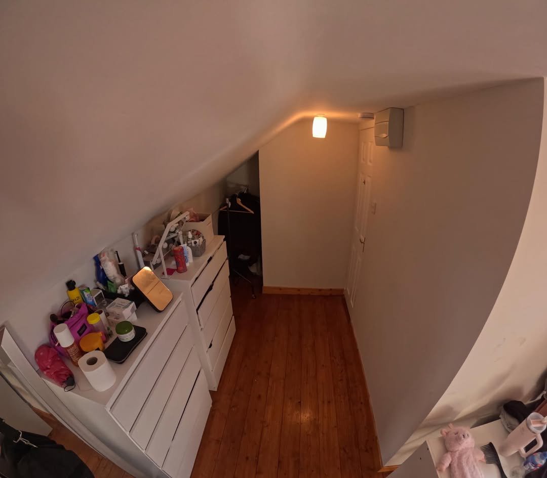 Attic storage space with white drawers, wooden floor, and sloped ceiling.