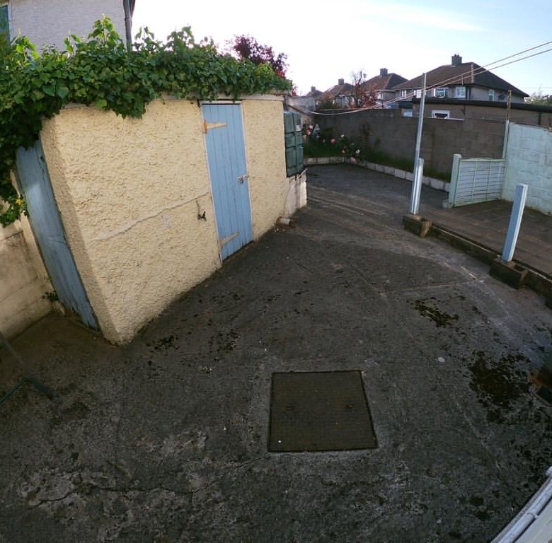 Backyard with shed, concrete patio, and utility box against a house.