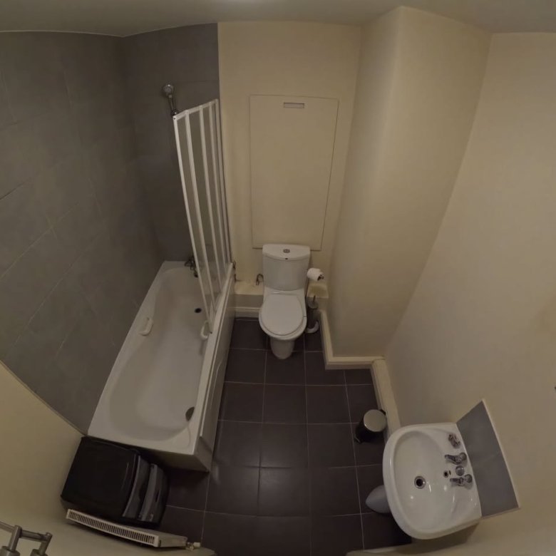 Bathroom interior with toilet, sink, and bathtub with shower screen.
