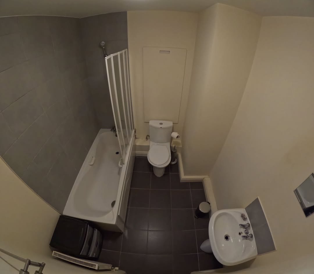 Bathroom interior with toilet, sink, and bathtub with shower screen.