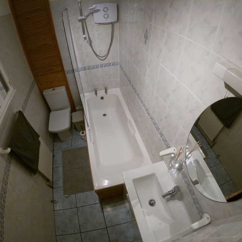 Bathroom interior with tub, toilet, sink, and cabinet. Tiled walls and floor.