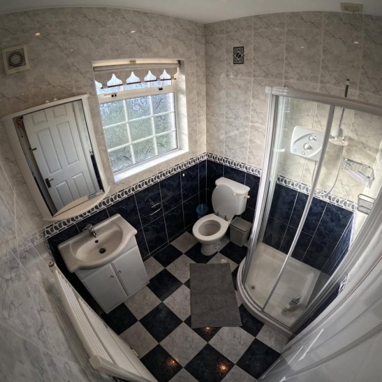 Bathroom with shower, toilet, sink, black and white tile floor.