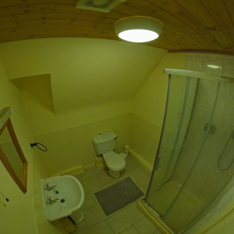 Bathroom with toilet, sink, and shower in a cozy space.