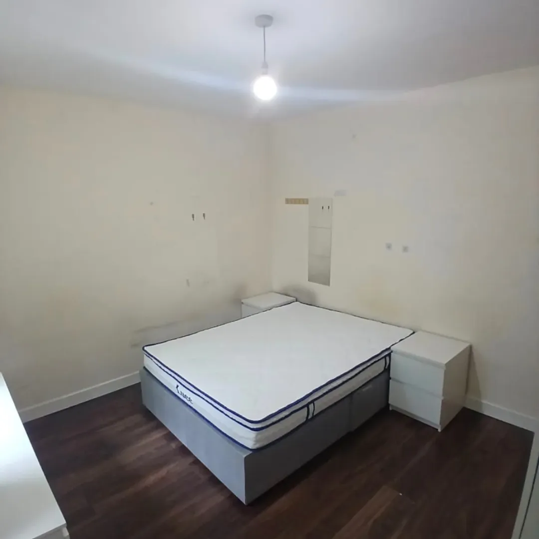 Bedroom with bed, two nightstands, and dark wood floors. Minimalist decor.