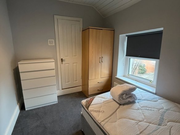 Bedroom with bed, wardrobe, chest of drawers, and window with blind.