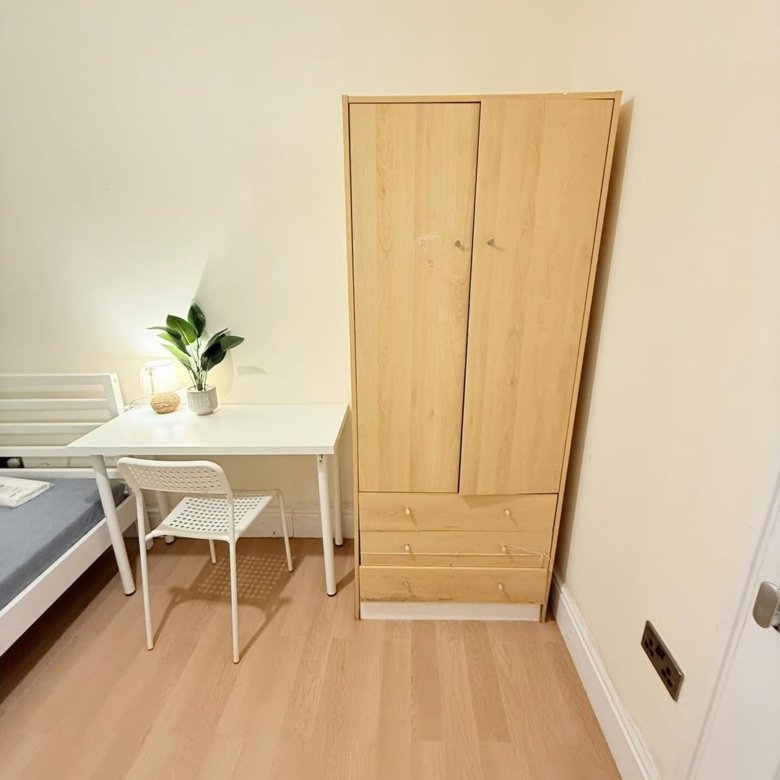 Bedroom corner with wardrobe, desk, chair, and bed. Light wood furniture, minimalist design.