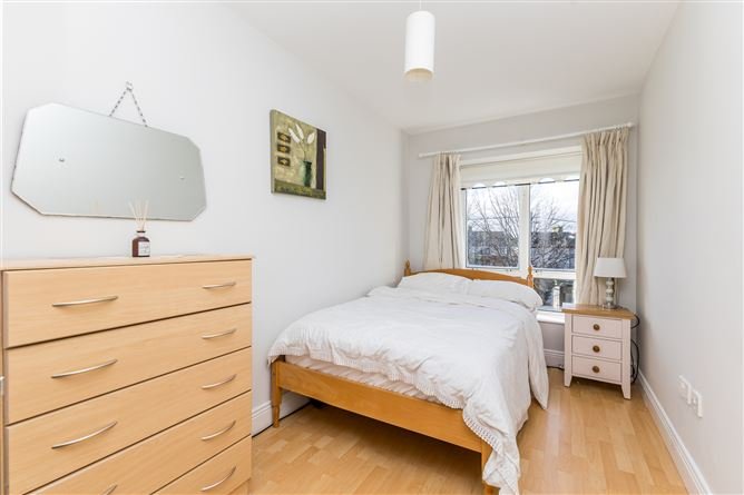 Cozy bedroom with double bed, dresser, and window. Bright, neutral decor.