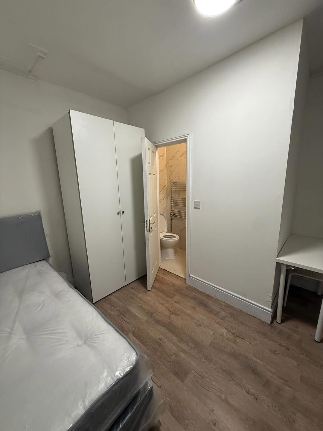 Bedroom with bed, wardrobe, desk, and ensuite bathroom.