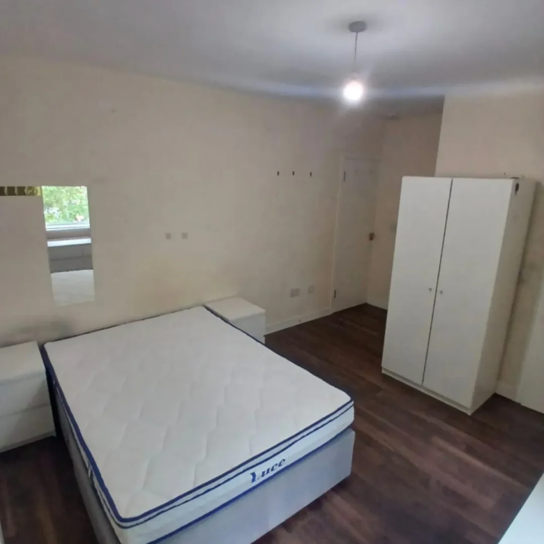 Bedroom interior with bed, wardrobe, and bedside tables.