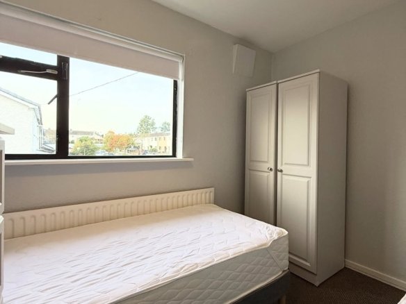 Bedroom interior with bed, wardrobe, and window. Neutral color scheme, carpeted floor.