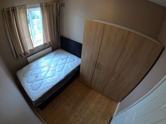 Bedroom interior with bed, wardrobe, and window. Neutral tones and wooden floor.