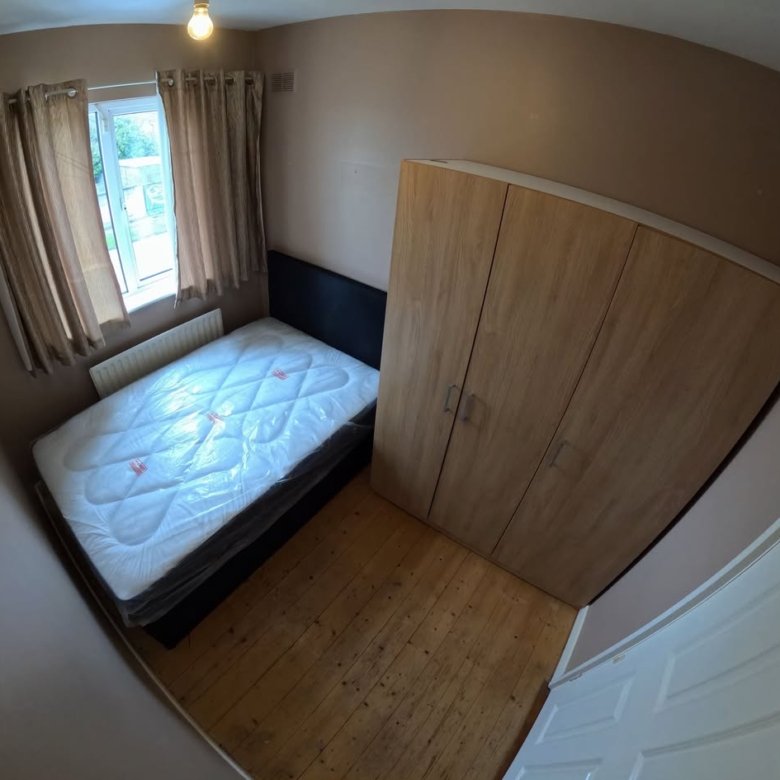 Bedroom interior with bed, wardrobe, and window. Neutral tones and wooden floor.