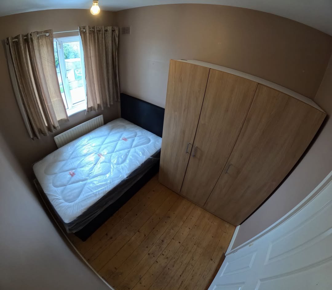 Bedroom interior with bed, wardrobe, and window. Neutral tones and wooden floor.