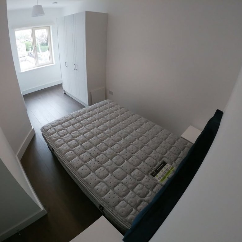 Bedroom with mattress, wardrobe, and window. Bright, minimalist interior design.