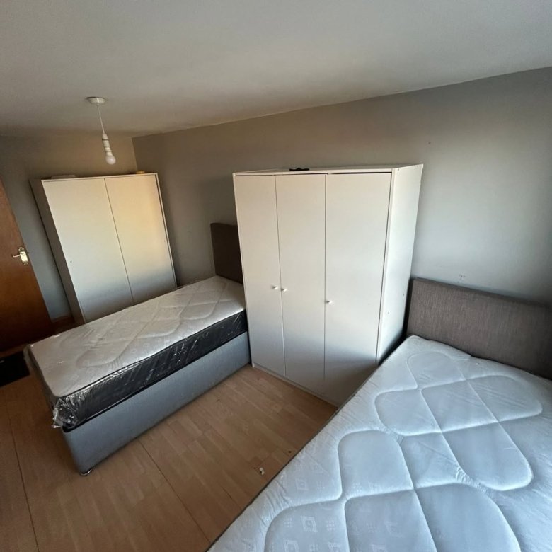Bedroom with two single beds and white wardrobes.