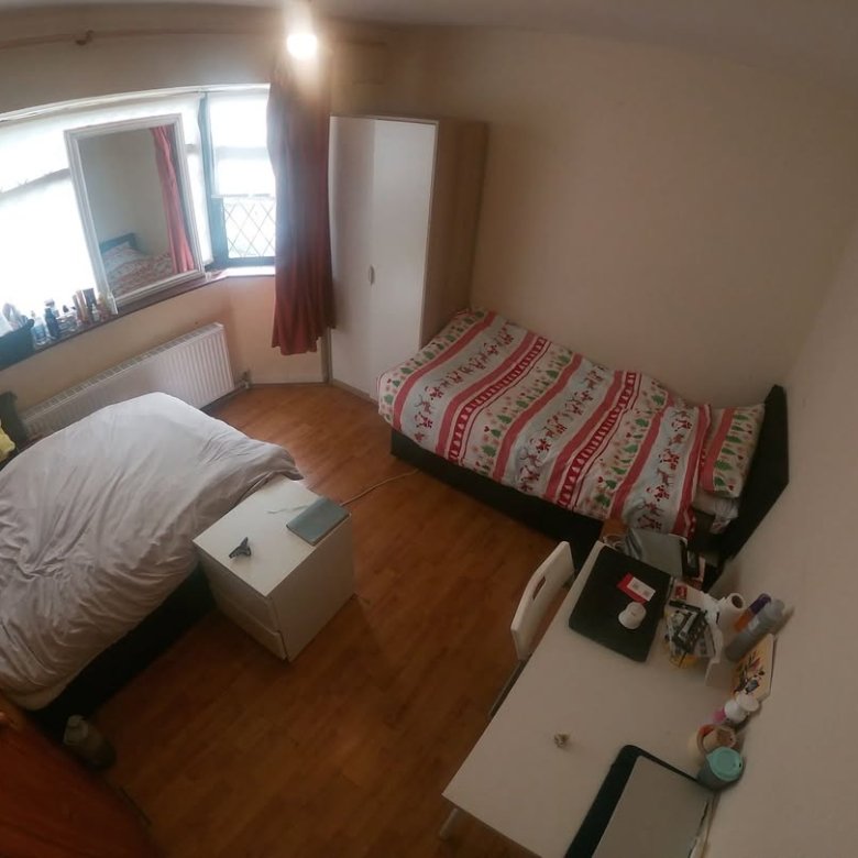 Cozy bedroom with two beds, desk, and natural light from window.