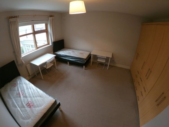 Bedroom with two beds, desks, wardrobe, and natural light.