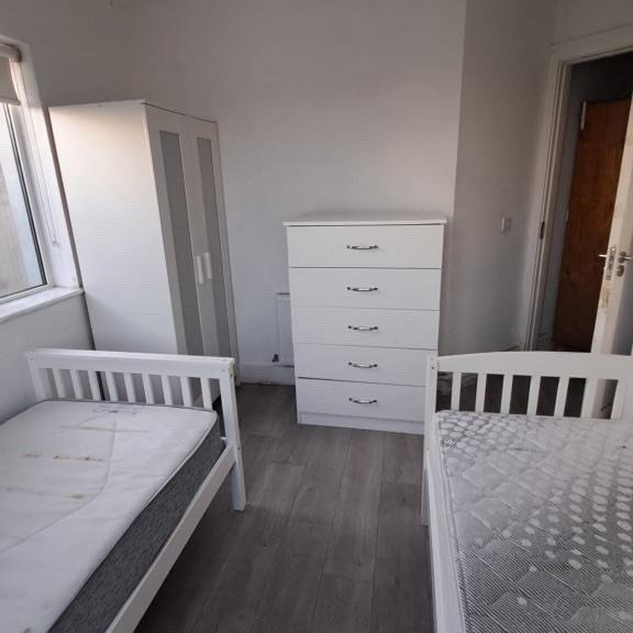 Bedroom with two beds, white dresser, and wardrobe.