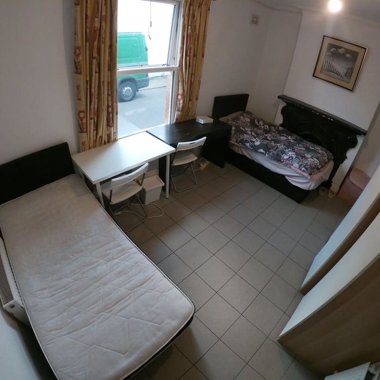 Cozy bedroom with two single beds, desks, and a window view.