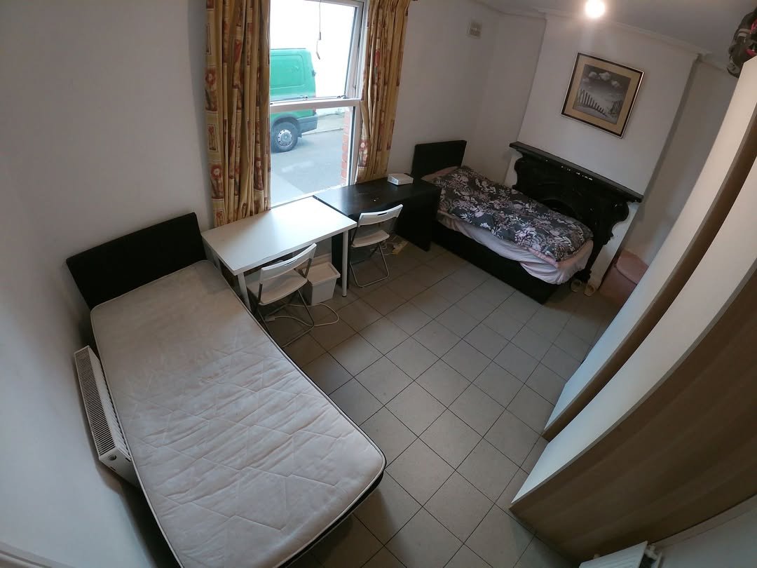 Cozy bedroom with two single beds, desks, and a window view.