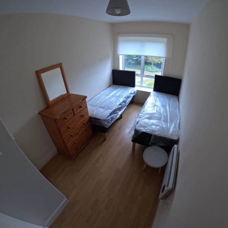 Bedroom with two single beds, dresser, and window.