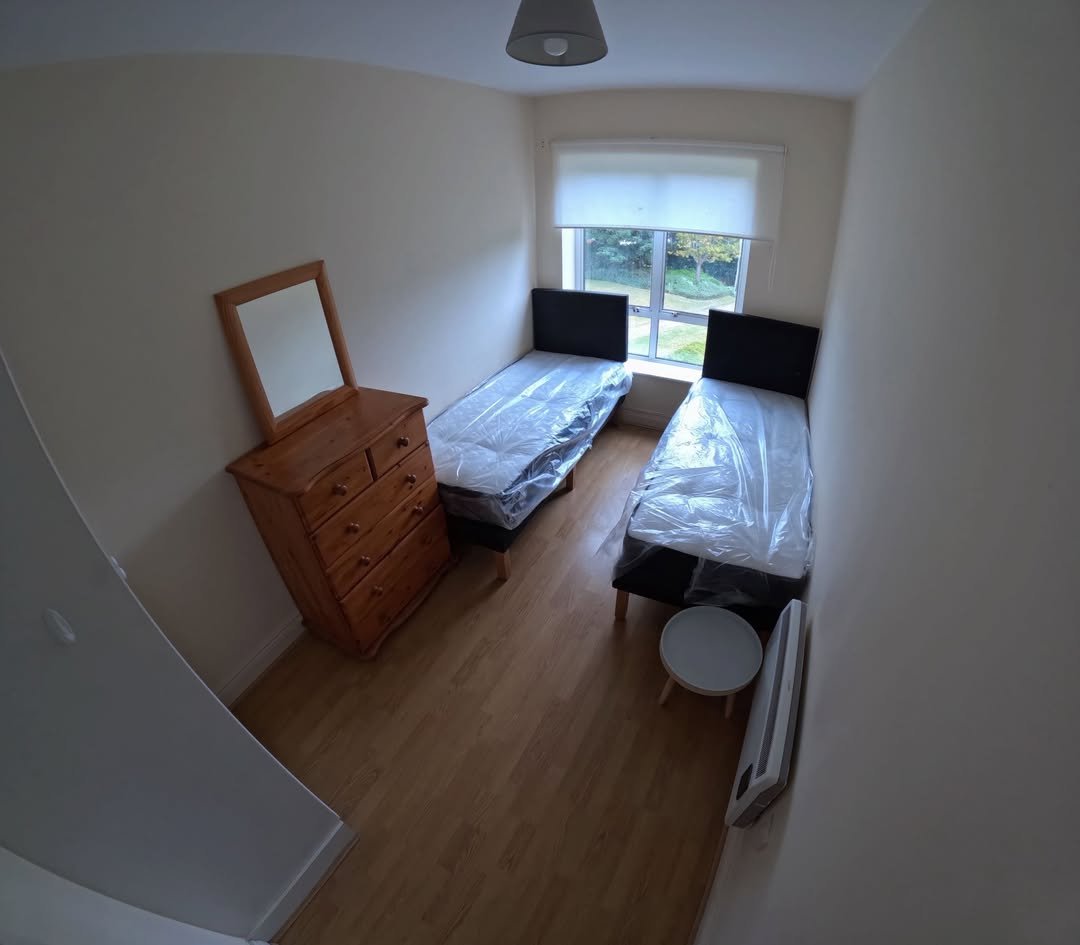 Bedroom with two single beds, dresser, and window.