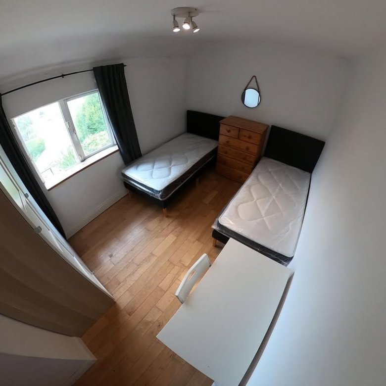 Bedroom with two single beds, dresser, desk, and wood flooring.