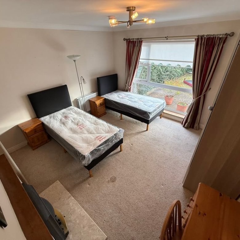 Bedroom with two single beds, bedside tables, window, and neutral decor.