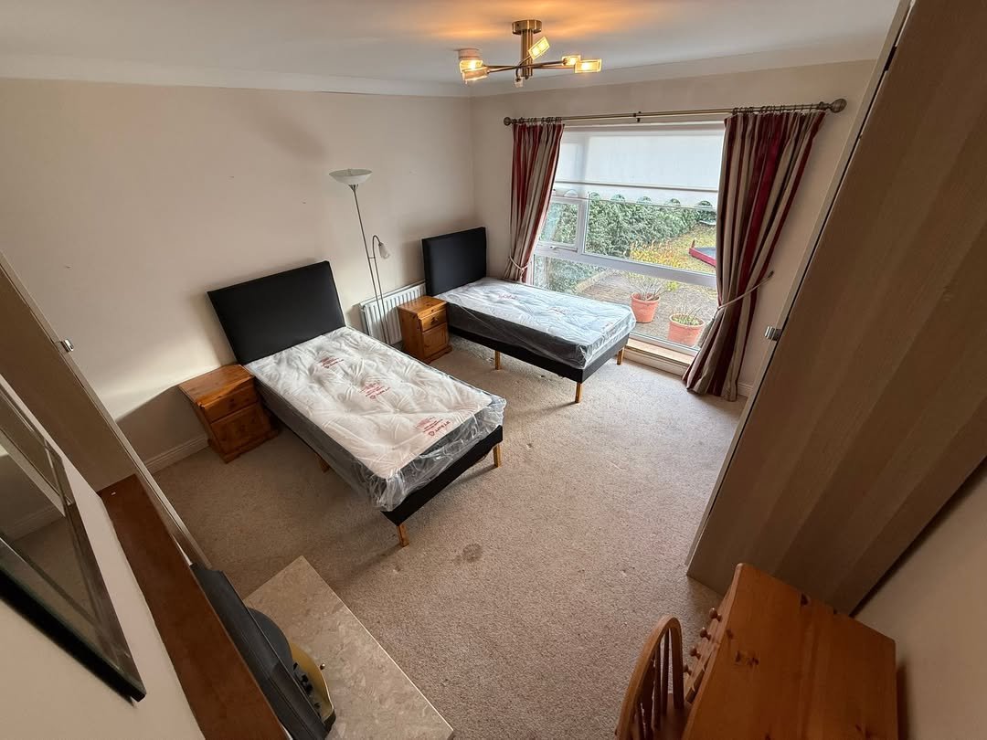 Bedroom with two single beds, bedside tables, window, and neutral decor.