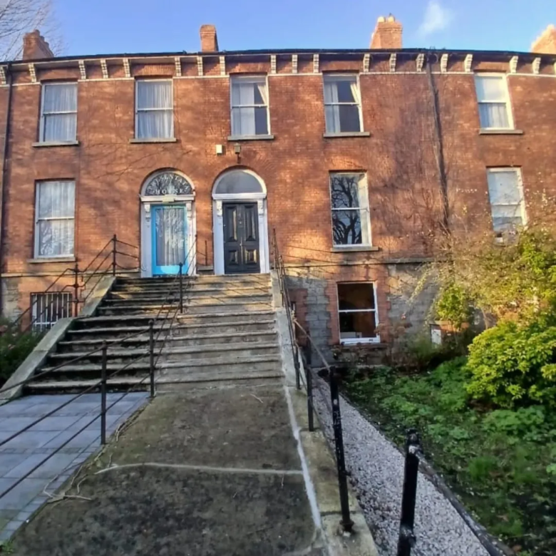 Large brick building with steps leading to two entrances, one blue, one black.