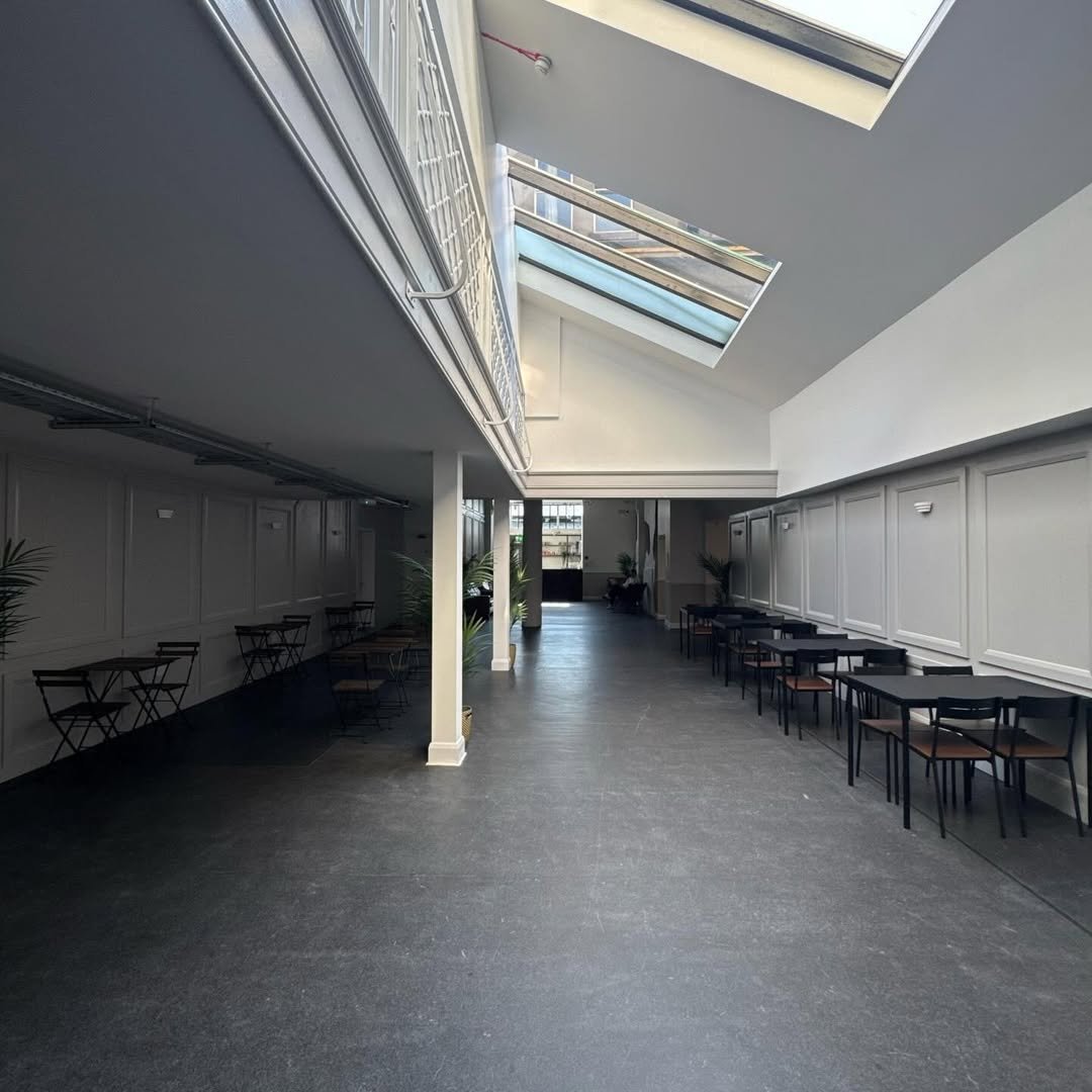 Bright cafe interior with skylight, tables, chairs, and white paneled walls. Modern, spacious design.