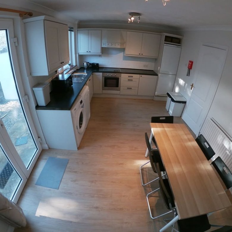 Bright kitchen with dining area, white cabinets, and large window.