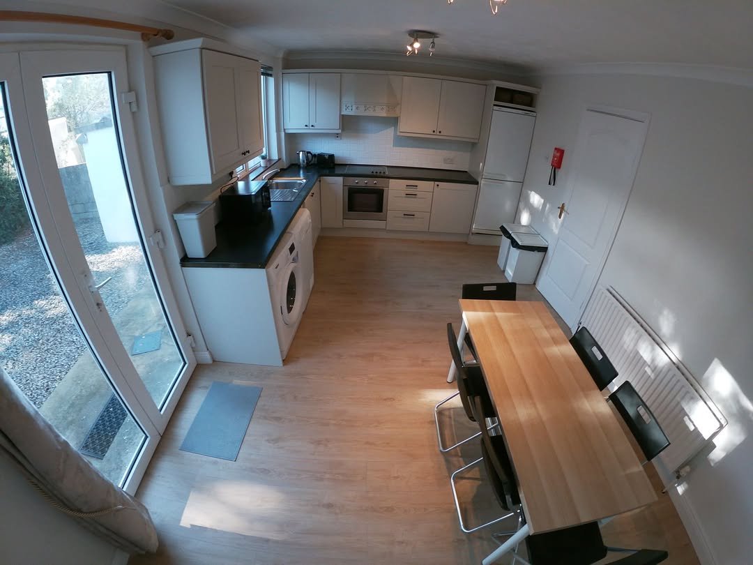 Bright kitchen with dining area, white cabinets, and large window.