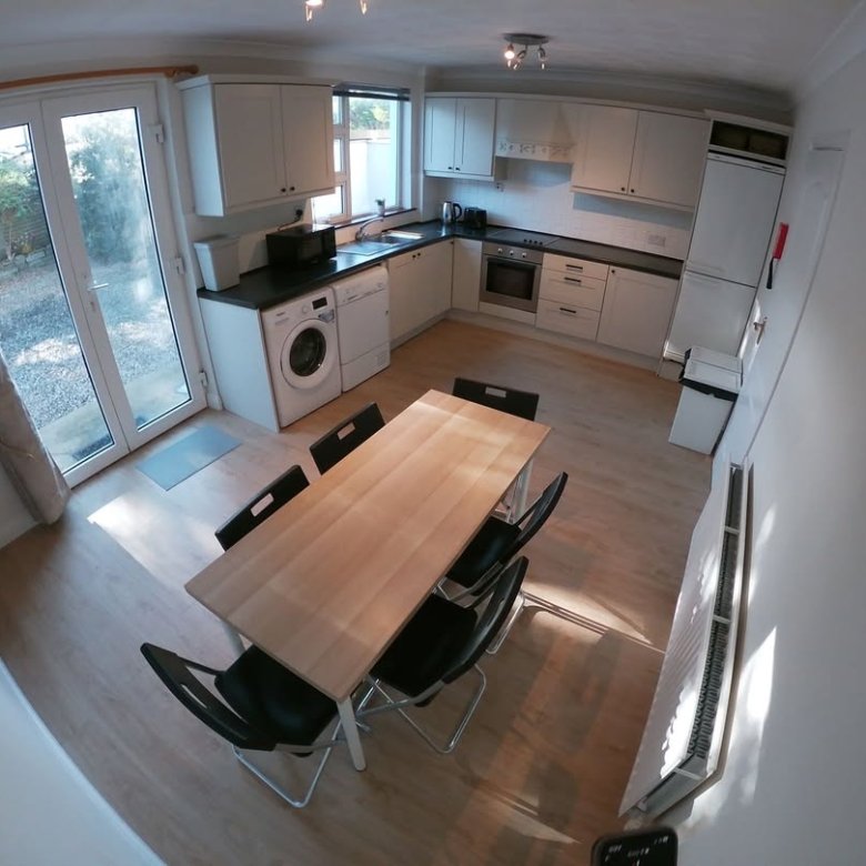 Bright kitchen with dining table, washing machine, and patio doors to garden.