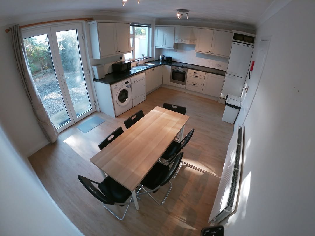 Bright kitchen with dining table, washing machine, and patio doors to garden.