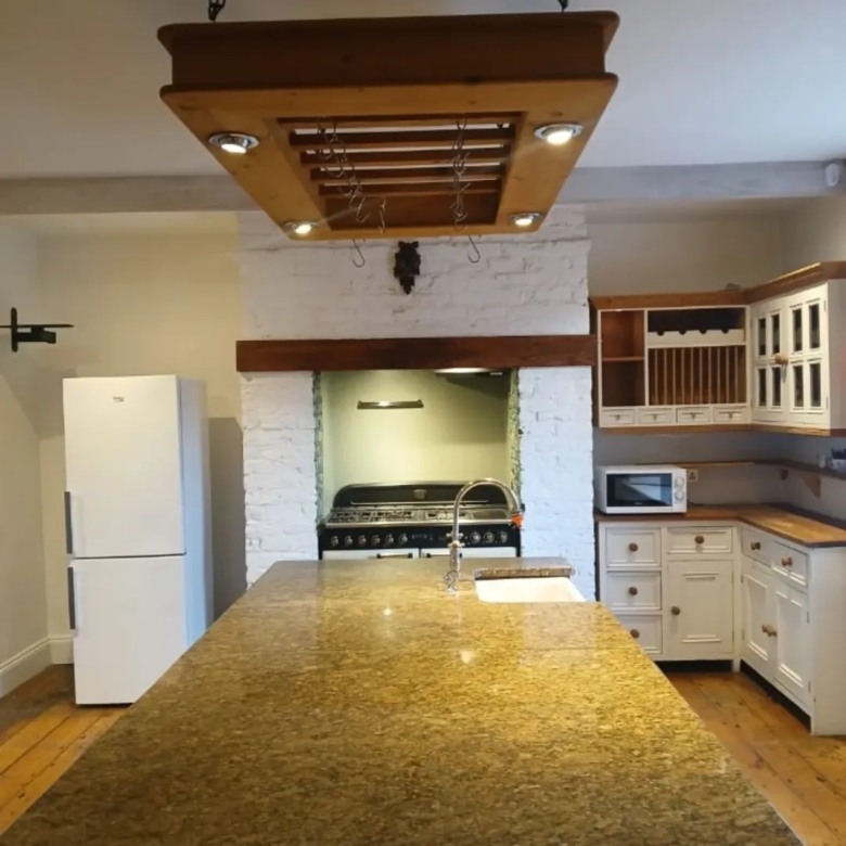 Bright kitchen with large island, white cabinets, and range cooker.