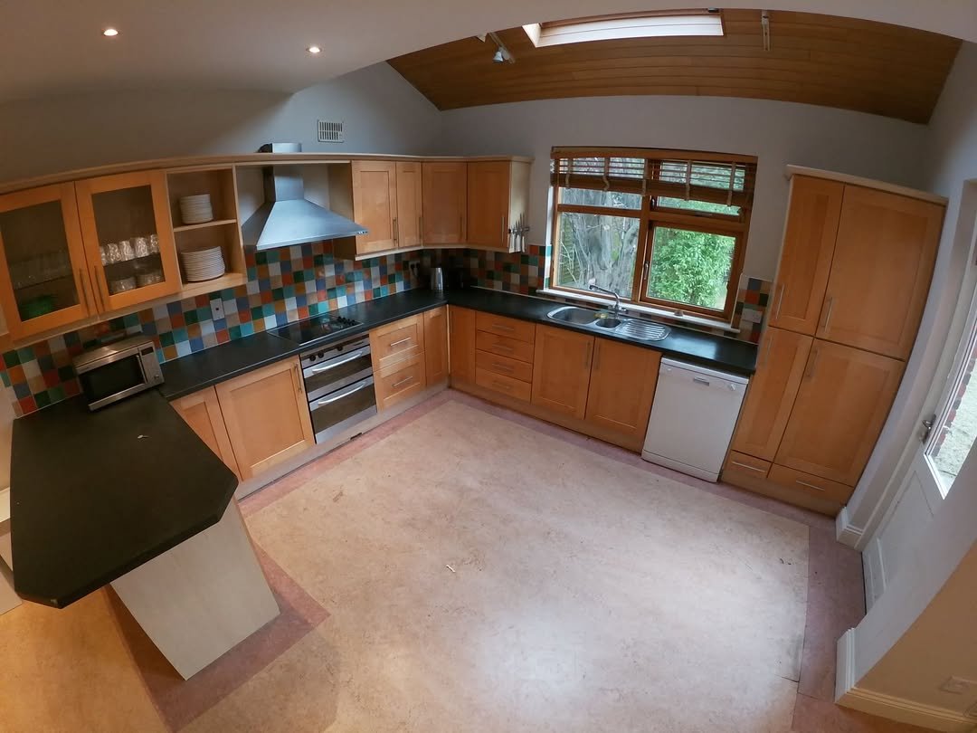 Bright kitchen with wooden cabinets, skylight, and black countertop island.