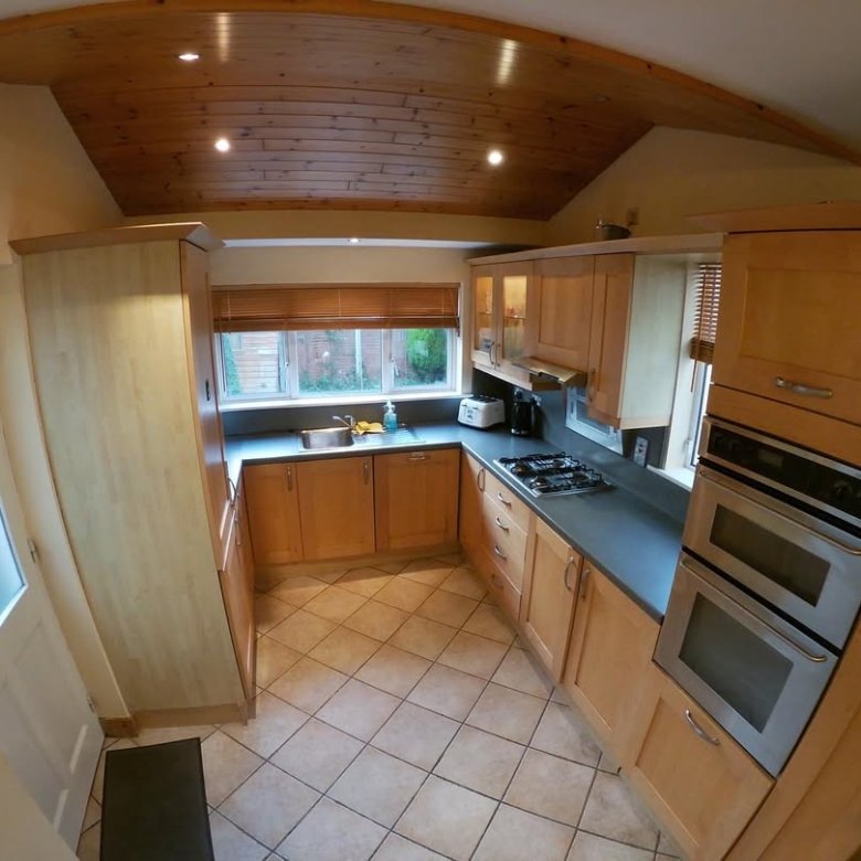 Bright kitchen with wooden cabinets, tile floor, and natural light from window.