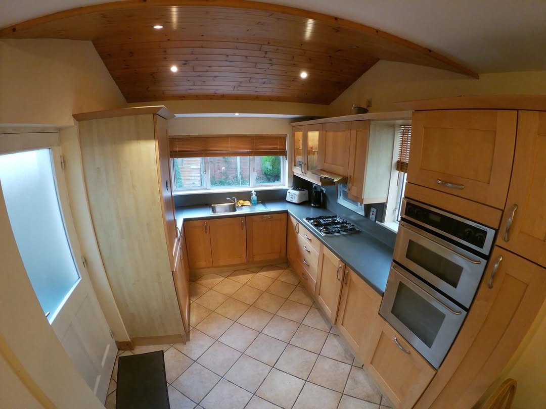 Bright kitchen with wooden cabinets, tile floor, and natural light from window.